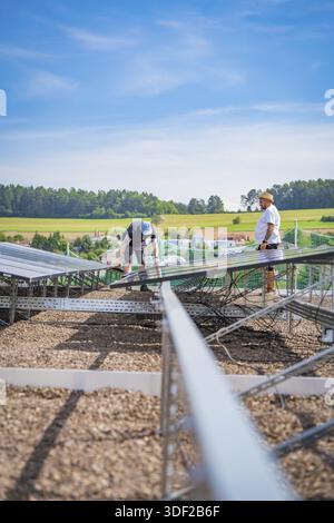 Two men install solar panels on a construction site surrounded by rural fields, new Park and Ride Calw Heumaden car park on the new Hermann Hessebahn Stock Photo