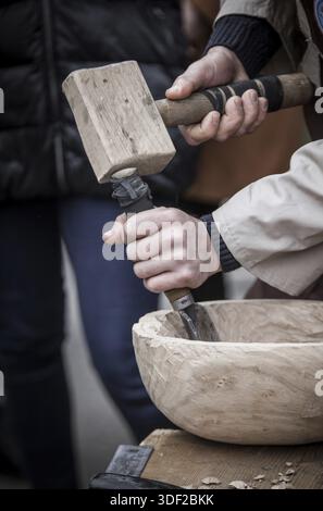 Man's hands of the joiner do a bowl, beats a hammer on a chisel Stock Photo