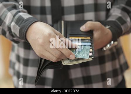 Man's hand pulls out a credit card from a black purse Stock Photo