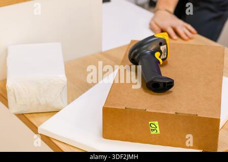 Closeup of delivery box, barcode reader, and packing materials on desk Stock Photo