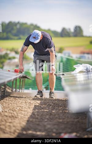 A worker on a construction site measures something while installing solar systems, new park and ride parking garage Calw Heumaden at the new Hermann H Stock Photo