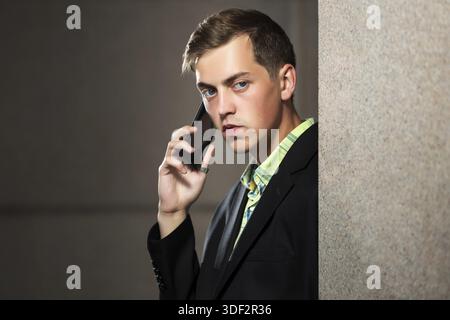 Young man calling on mobile phone at the wall Stock Photo