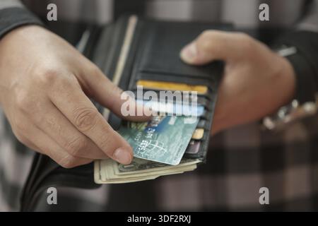 Man's hand pulls out a credit card from a black purse Stock Photo