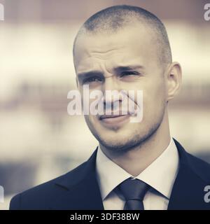 Young handsome businessman in dark blue suit jacket walking in city street Stock Photo