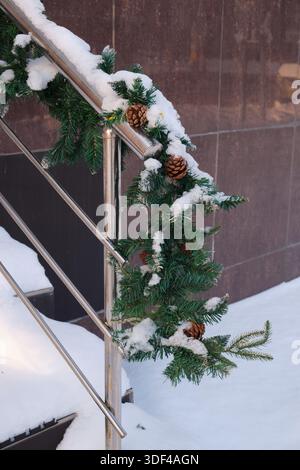 Christmas tree branches with cones in the snow on stairs. Winter background Stock Photo