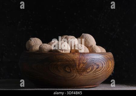 Walnuts in wooden bowl on black background. Close up Stock Photo