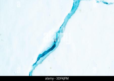 Macro photography of a deep fissure on a pale blue textured wall, representing damage, aging, or structural failure in buildings. Stock Photo