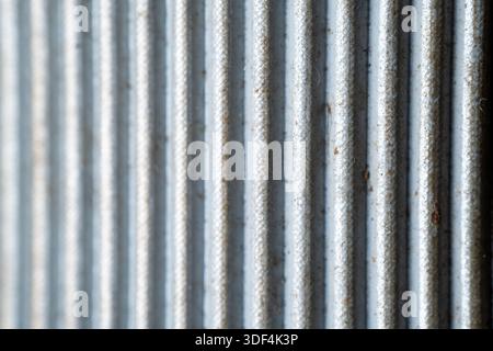 A detailed macro shot of a grey corrugated surface featuring repetitive vertical lines, metallic texture, and industrial design elements. Stock Photo