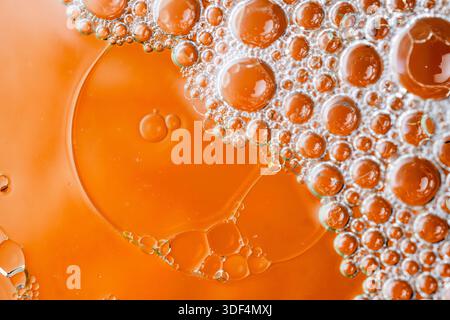 Macro shot of organic liquid bubbles in warm orange and gold tones, creating a beautiful abstract texture with depth and soft lighting. Stock Photo