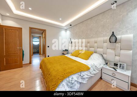 an image of a large bed with golden sheet and pillows with private bathroom in holiday home Stock Photo