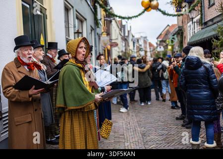 Deventer, Overijssel, Netherlands - 14.12.2025: At the Charles Dickens Festival. Victorian carolers sing on a festive street garlands, costumes, and w Stock Photo