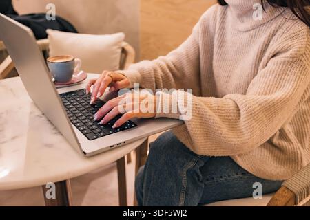 Woman typing on laptop in cafe working remotely Stock Photo