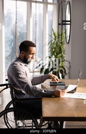 Focused African business professional man with paraplegia working in office Stock Photo