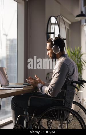 African American professional man with disability using headphones and laptop Stock Photo