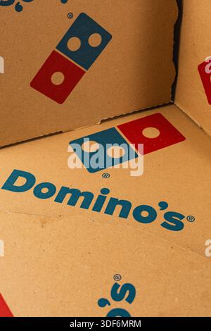 Lviv Ukraine 12.08.2025 Several empty pizza boxes are stacked against a wall in a corner during a casual gathering. The boxes are labeled with a pizza Stock Photo