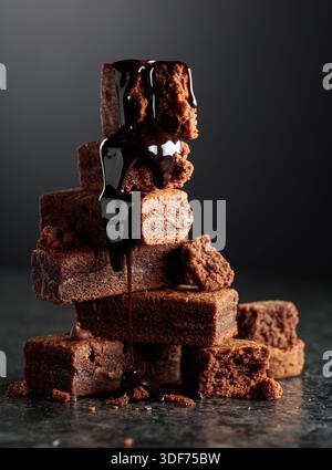 Brownie pieces on a black background. Melted chocolate drips down the brownie. Stock Photo