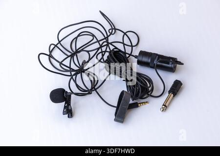Components of a Boya BY-M1 omnidirectional lavalier condenser microphone kit with 6m cable, 3.5mm jack, 1/4" adapter, and power module on white backgr Stock Photo