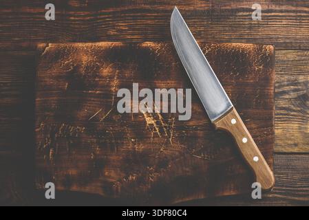 Knife over rustic wooden cutting board Stock Photo