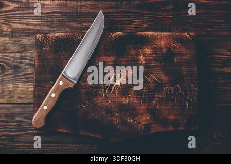 Knife over rustic wooden cutting board. View from above Stock Photo