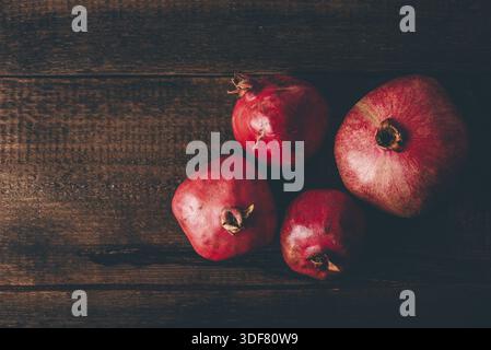 Four ripe pomegranate on rustic wooden table Stock Photo