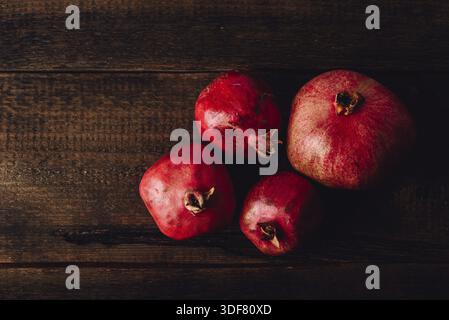 Four ripe pomegranate on rustic wooden table Stock Photo