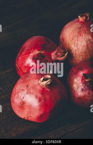 Four ripe pomegranate on rustic wooden table Stock Photo