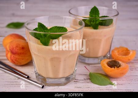 Apricot smoothie in glasses on a white wooden background. Stock Photo