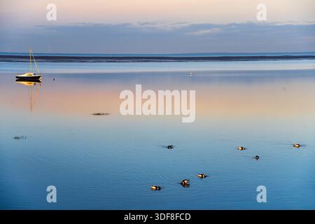 Small sailing boat named Sea Spray at mooring on the calm evening waters of the Liverpool Bay at Hoylake on the Wirral. Stock Photo