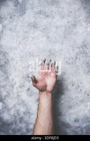Man hand covered with paint on gray concrete wall background Stock Photo