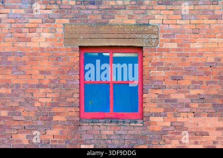 Red window frame in a brick wall, UK Stock Photo