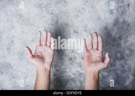 Man hands covered with paint on gray concrete wall background Stock Photo