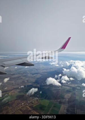 Breathtaking landing with a plane wing banking through thick, foggy clouds. View through airplane window during flight, with dynamic aerial perspectiv Stock Photo