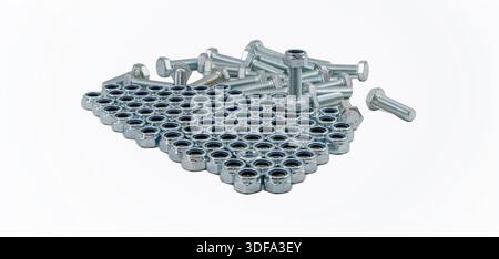 Hex nuts arranged in metal grid with bolts forming industrial hardware composition Stock Photo