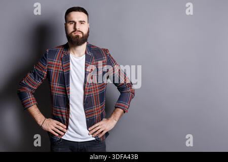 Serious bearded man posing with hands on hips Stock Photo