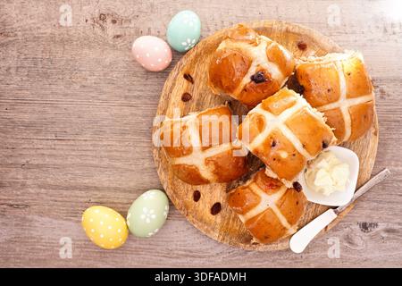 Fresh homemade Hot Cross Buns on a wooden plate. Above view table scene on a wood background. Easter food concept. Stock Photo