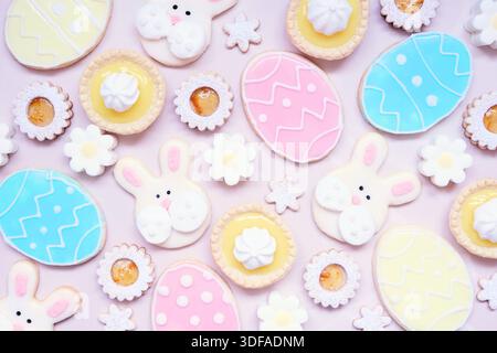 Easter or spring themed baking background with assorted cookies and sweet desserts. Overhead view on a pink stone background. Stock Photo