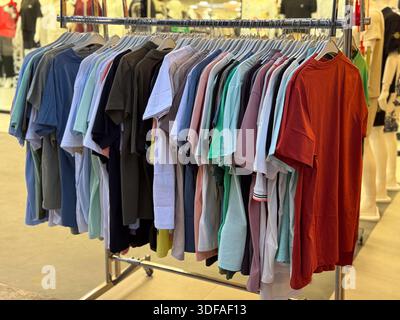 Colorful t-shorts hanging on a rack in a fashion store. Clothing variety, retail shopping, seasonal apparel, textile display and wardrobe selection. Stock Photo