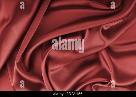 Crumpled, wrinkled red colored glossy silk satin with wave drapery.. Shiny smooth fabric with soft folds, cloth texture . Elegant rich background, wal Stock Photo