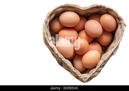 Free range chicken eggs in a heart shaped water hyacinth wicker basket. Isolated on a white background Stock Photo