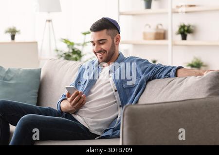 Closeup of smiling jewish man using smartphone at home Stock Photo