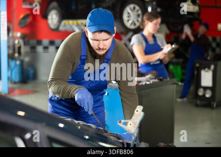 Professional mechanic man in uniform repairing car in auto repair garage Stock Photo