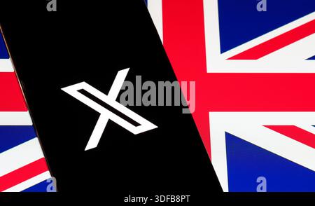 X logo glowing on smartphone lying on British flag fabric, rebranded Twitter icon and digital media concept in Britain. Stafford, United Kingdom, Janu Stock Photo