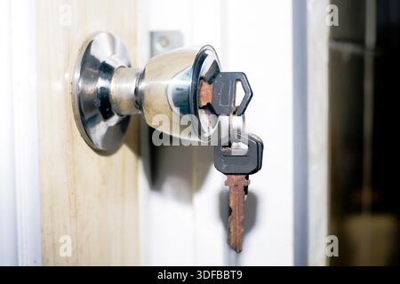 close up of rusty key hanging on keyhole door lock Stock Photo