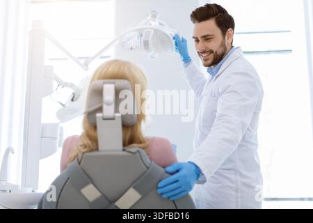 Young handsome dentist comforting female patient sitting in chair Stock Photo