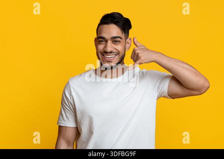 Cheerful middle eastern young man showing call me gesture Stock Photo
