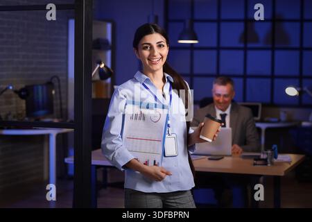 Female business analyst with diagrams in office at night. Data science concept Stock Photo
