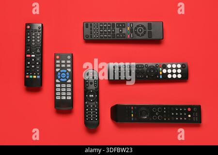 Different modern TV remote controls on red background Stock Photo