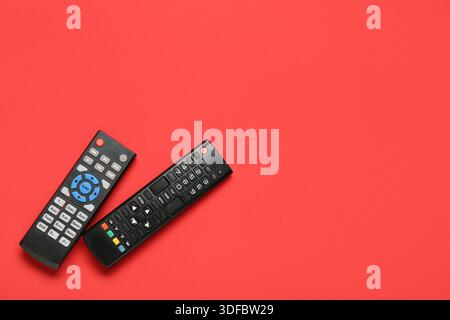 Different modern TV remote controls on red background Stock Photo