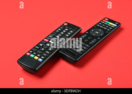 Modern TV remote controls on red background Stock Photo
