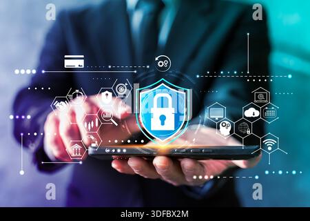 Businessman holding smartphone with shield lock interface and network icons, representing mobile security, encryption, secure payments, cloud protecti Stock Photo